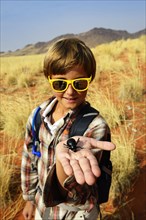 Boy holds a black beetle in the hand