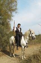 Gardian or traditional bull herder in typical working clothes on a Camargue horse