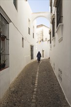 Nun in an alley with whitewashed houses