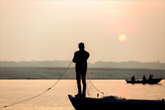 Fisherman throws net in the sunrise on Ganges river