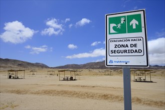 Tsunami warning sign near picnic area on the beach