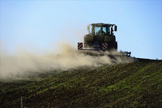 Farmer harrows field with tractor