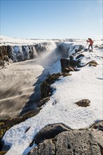 Photographing man at the edge of the Selfoss waterfall in winter