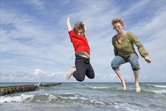 Mother and son jump on the beach