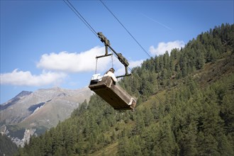 A woman travels in the material cable car of the Litzlhofalm in the Seidwinkl valley in the Hohe Tauern National Park