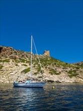 Sailboat in the harbour behind it Cabrera Castle