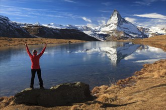 A woman stands with her arms outstretched on a rock