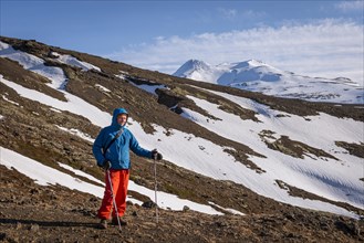 Hiker in front of a snowy landscape near Hvalfjaroarsveit