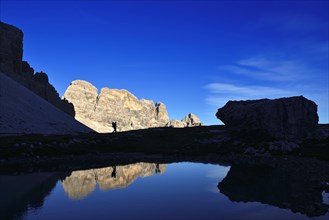 Hiker on the lake in the backlight