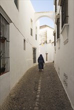Nun in an alley with whitewashed houses
