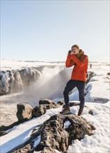 Photographing Man at Selfoss Waterfall in Winter