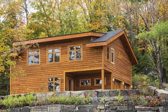 Luxurious stained cedar and timber wood 2-car garage with upstairs floor and landscaping in autumn