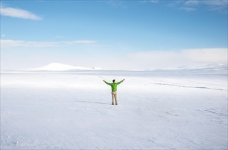 Young man stands alone in snowy landscape