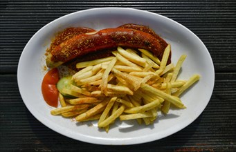 Curry sausage with French fries on plates