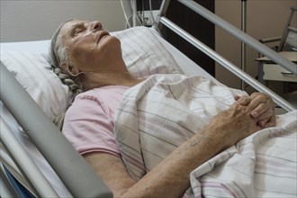Sleeping senior citizen with respiratory tube in bed in hospital