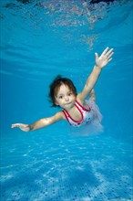 Little girl learns to swim underwater in the pool