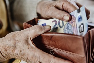 Senior citizen pulls a 20 euro note from her wallet