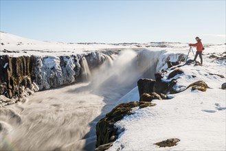 Photographing man at the edge of the Selfoss waterfall in winter