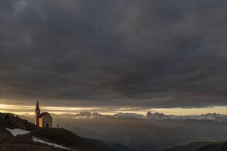 Latzfonser cross chapel at sunrise with dramatic clouds and South Tyrolean mountains