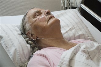 Sleeping senior citizen with respiratory tube in bed in hospital
