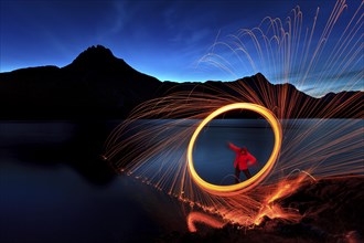 Man with hoop of fire with sparks on the shore of the Spullersee
