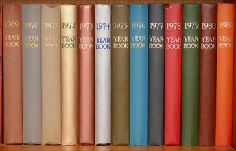 Year-books in different colors in a shelf