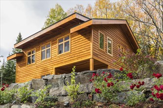 Luxurious stained cedar and timber wood 2-car garage with upstairs floor and landscaping in autumn