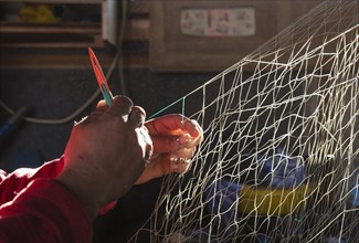 Fisherman repairs a net in his fishermans cottage