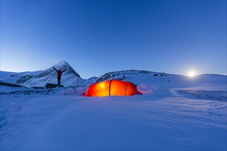 Tent with person at full moon in the snow