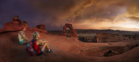 Hikers sit at Delicate Arch Arch