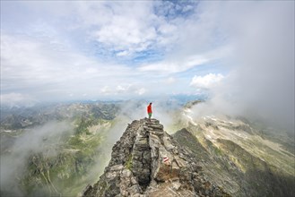 Hiker on the summit of the Hochgolling with rising fog