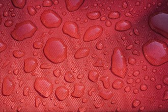 Close-up of raindrops on surface of water resistant red canvas material