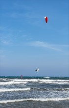Kitesurfer in the air over sea with waves