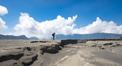 Young man is standing at an earth splinter and photographed