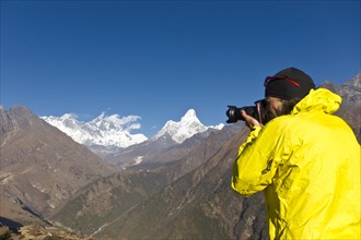 Photographer with yellow jacket taking a photograph of Mount Everest Mountain