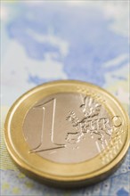 One Euro coin on top of twenty Euro paper currency bank note