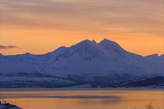 Tromsoysund with snowy mountains at sunset