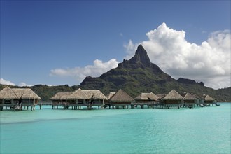 Water bungalows in turquoise lagoon in front of Mont Otemanu