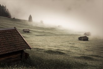 Small cabin on mountain meadow in the fog