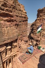 Tourist sits on a carpet and looks from above into the gorge Siq