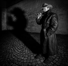 Man with hat and leather coat smokes cigar