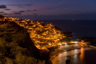 Blue hour with illuminated town by the sea