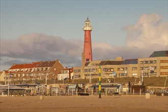 Lighthouse on beach behind buildings