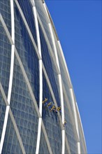 Window cleaners hang on "The Coin" building
