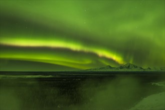 Aurora over the fog shrouded Copper River and mounts Sanford Drum and Wrangell