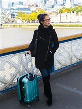 Young woman with suitcase standing on a bridge