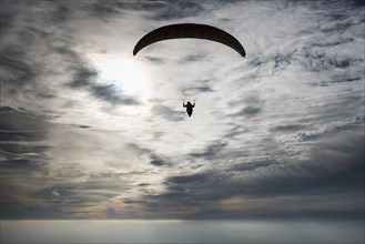 Paraglider against cloudy sky