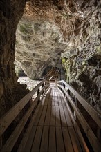Covered wooden bridge leads into the limestone cave Smoo Cave