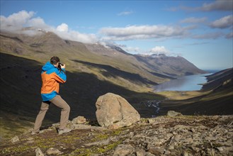 Photographer photographs view from Mjoafjaroarheioi Pass onto Mjoifjorour Fjord