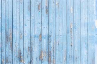 Wooden wall of strongly weathered vertically laid blue single boards